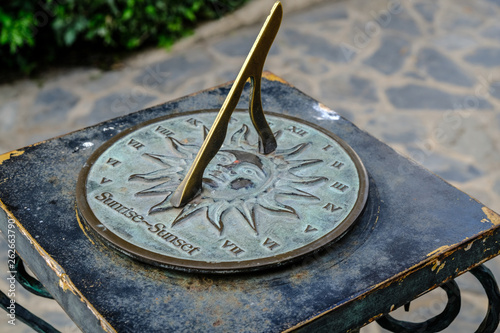Close-up of a brass sundial mounted on a stone plinth in a garden, Sundial in the Summer sun.