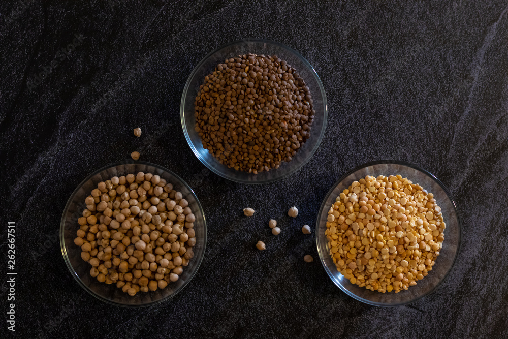 chickpeas lentils and peas in transparent plates on a dark background chickpeas lentils and peas in transparent plates on a dark background