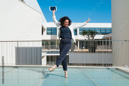 Portrait of dancing female executive with digital tablet