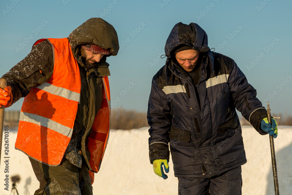 Two workers in overalls at a construction site Two workers in overalls at a construction site