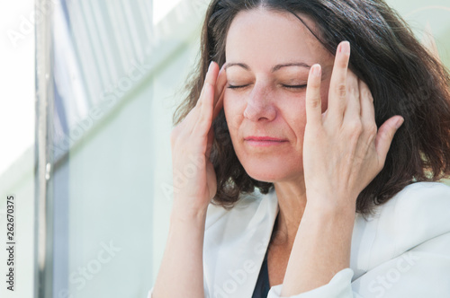 Close up shot of woman holding hands at head, having headache