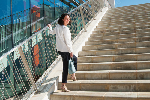 Smiling woman standing at stairs, turning head back to camera