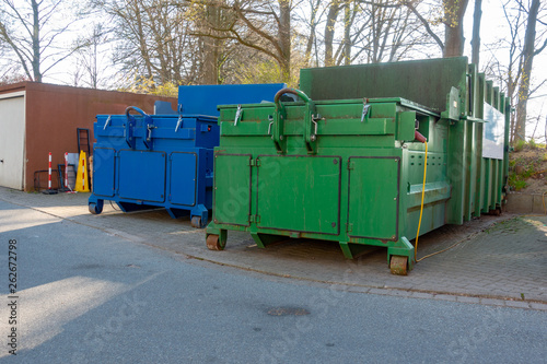 two garbage compactors are standing in the courtyard of a hospital