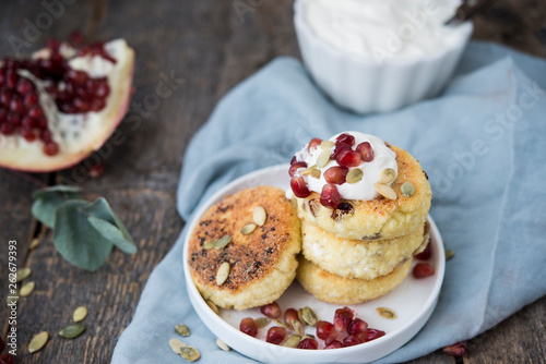 Cheesecakes for Breakfast decorated with pumpkin seeds and pomegranate seeds. Selective focus.