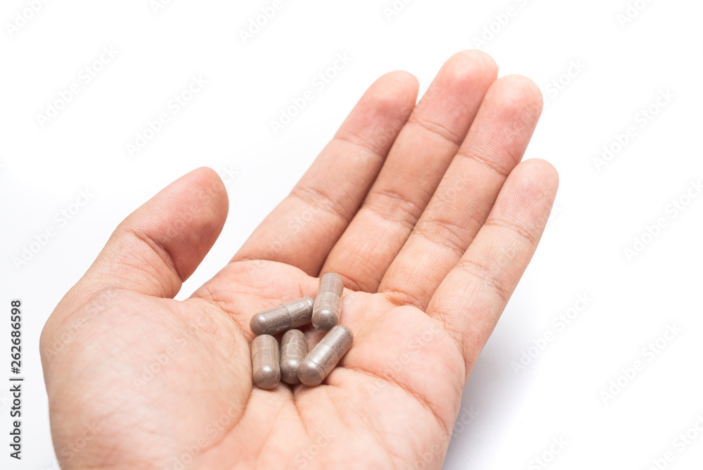 Hand holding herbal medicine in capsule isolate on white background. Herb black Galingale powder extract. Herbal medicine with open clear capsules. Alternative supplement for good healthy.