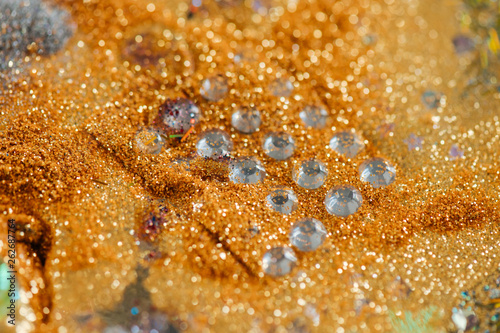 Paper with gluer transparent fake crystals being surrounded with golden glitter