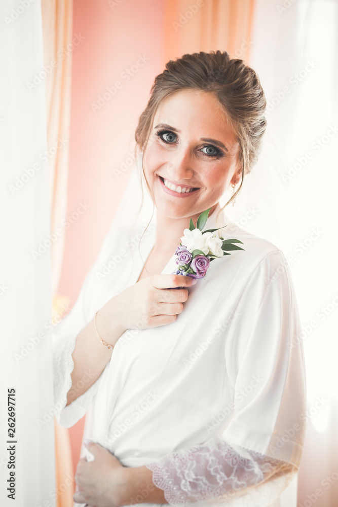 Gorgeous bride in robe posing and preparing for the wedding ceremony face in a room Gorgeous bride in robe posing and preparing for the wedding ceremony face in a room