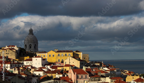 Colorful houses and red roofs of Alfama district and stormy sky in Lisbon, Portugal