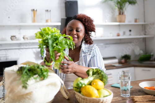 Amazing dark-skinned female person looking at salad