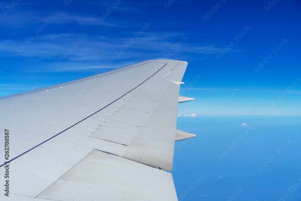 Obraz premium Wing of airplane flying in the sky on a clear day