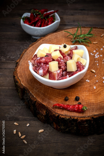 diced salami and cheese bowl on a wooden plate