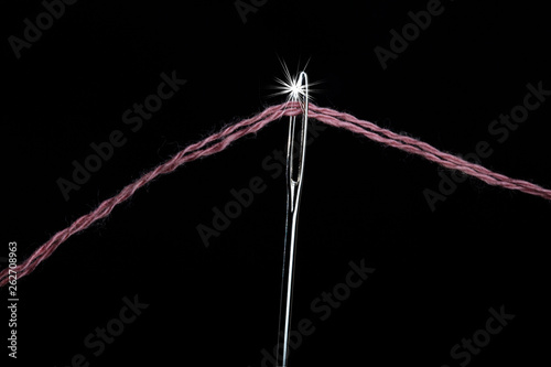 Needle with a large needle eye with wool thread on a black background. Close-up © Mikhail Pankov