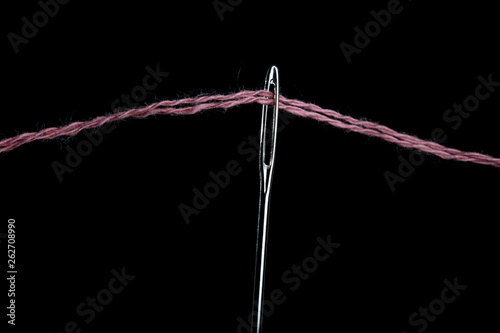 Needle with a large needle eye with wool thread on a black background. Close-up © Mikhail Pankov