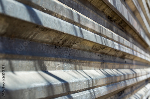 Fragment of an old fence of an abandoned construction site  made of metal sheets. Sunlit fragment of the fence