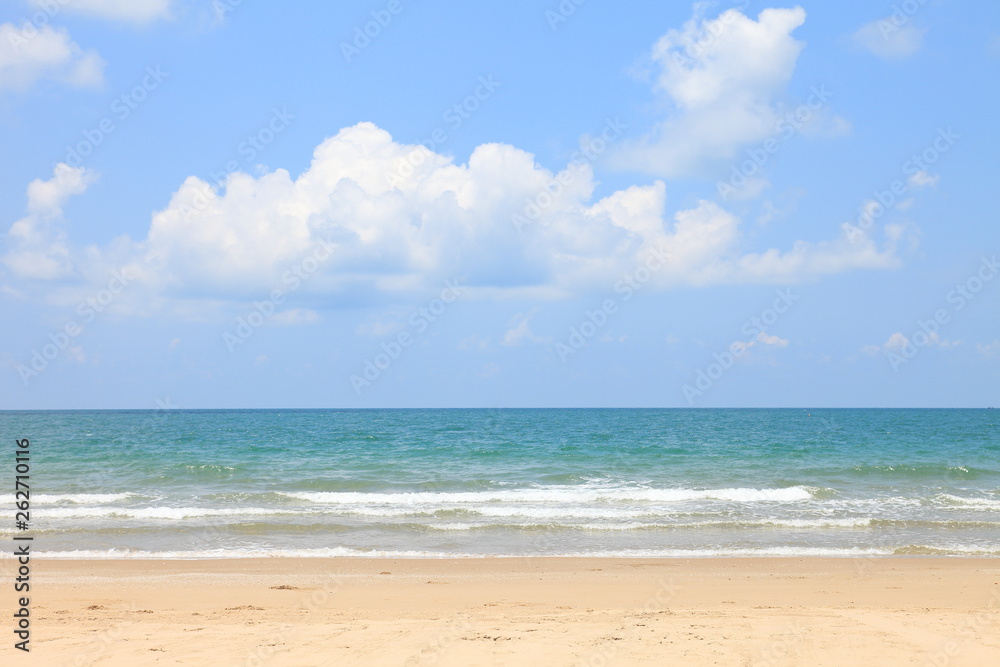 Sunny day at the beach with bright blue sky and fluffy white cloud on the sea horizon with copy space