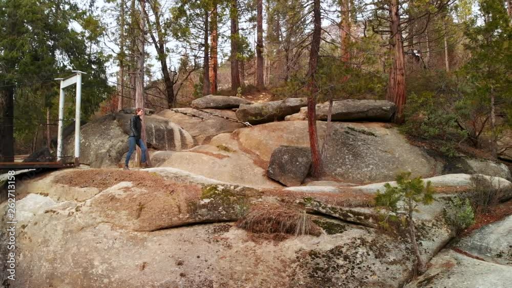 Aerial dolly shot to the right, following a mother and son scrambling over rocks and hiking down a trail Aerial dolly shot to the right, following a mother and son scrambling over rocks and hiking down a trail