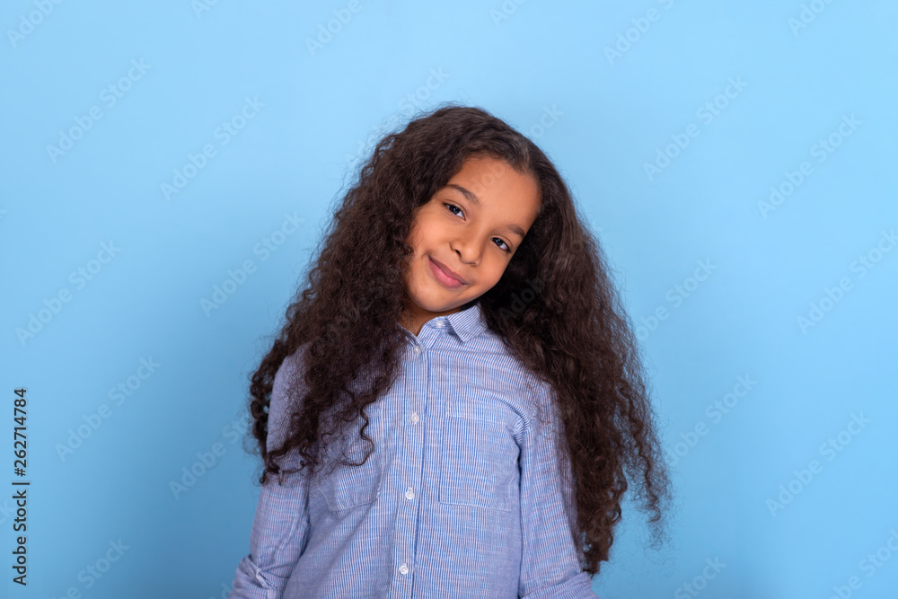 Waist up portrait of smiling frizzy girl wearing blue shirt on a blue background with copy space. Waist up portrait of smiling frizzy girl wearing blue shirt on a blue background with copy space.