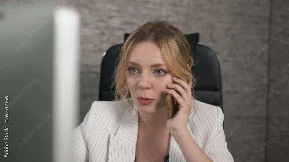 Good business talk. Cheerful young beautiful woman talking mobile phone and using laptop with smile while sitting at her working place Good business talk. Cheerful young beautiful woman talking mobile phone and using laptop with smile while sitting at her working place