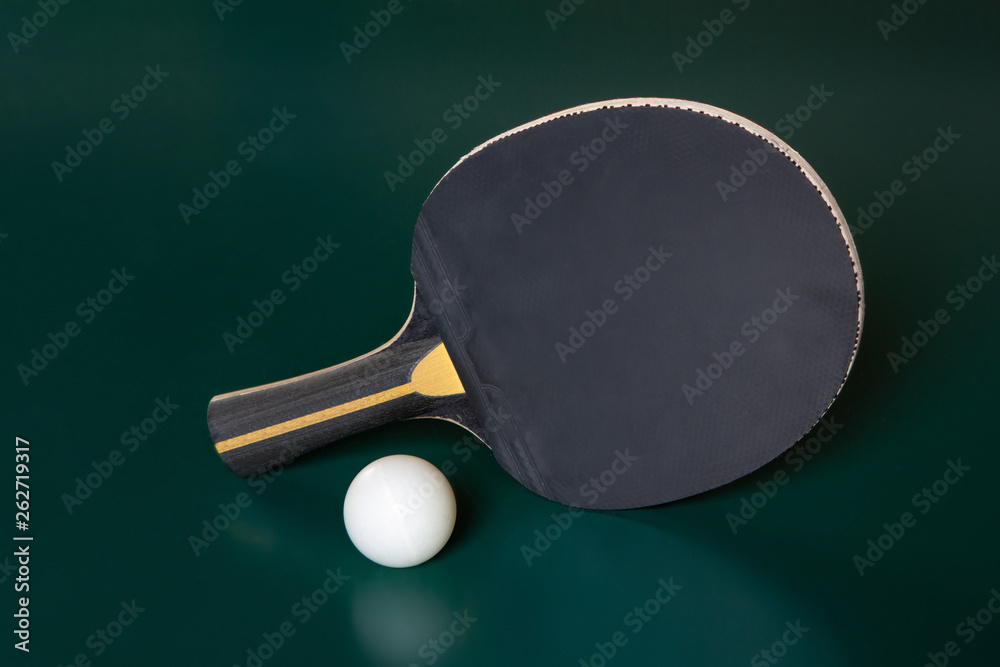 Blak ping-pong racket and a ball on a green table. Blak ping-pong racket and a ball on a green table.
