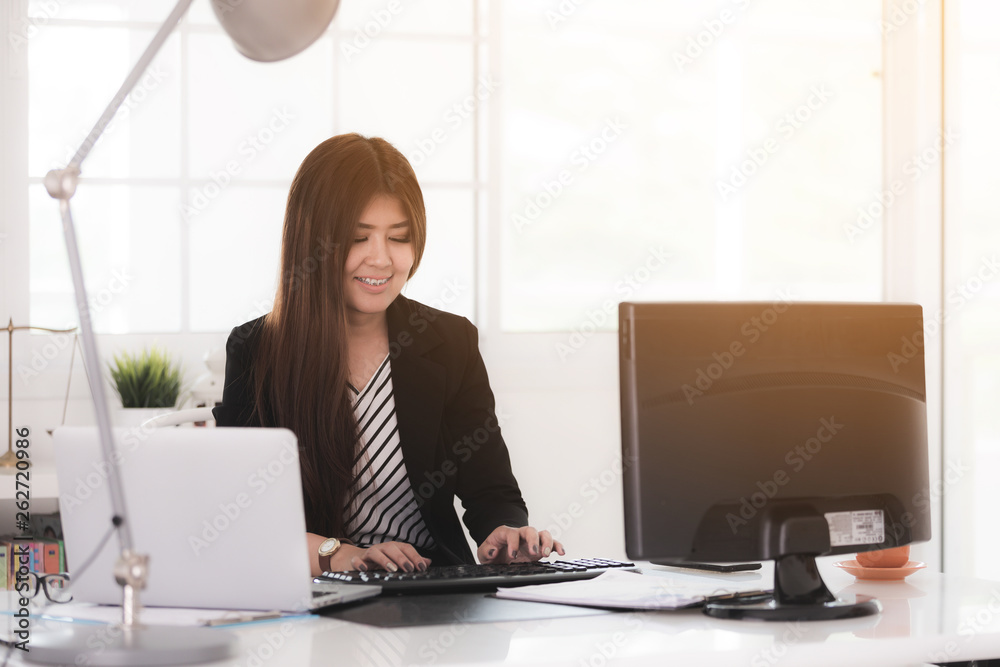 Portrait of a cheerful businesswoman sitting at the table in office .