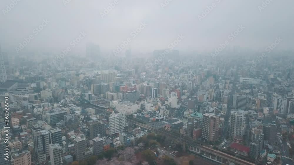 Drone panning around above the Tokyo city skyline at dusk after sunset on an overcast day among tall skyscrapers and hazy skies Drone panning around above the Tokyo city skyline at dusk after sunset on an overcast day among tall skyscrapers and hazy skies