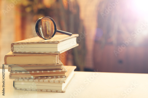 book and magnifying glass on wooden background photo