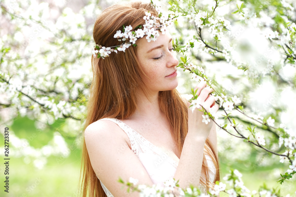 Beautiful redhead girl surrounded by blooming trees. Spring season is magic. Beautiful redhead girl surrounded by blooming trees. Spring season is magic.