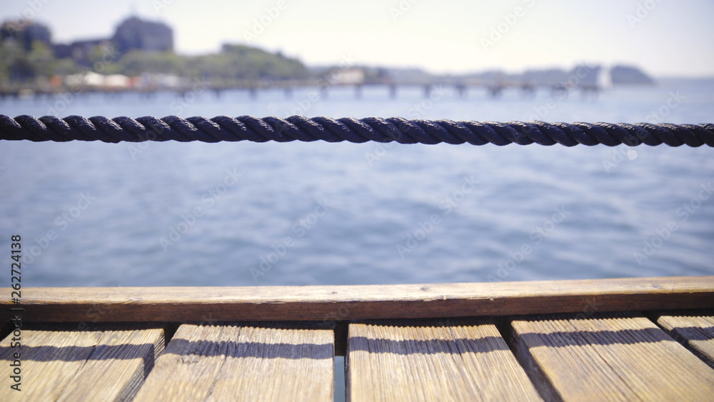 Naklejka premium Wooden pier and rope fence at the sea close-up