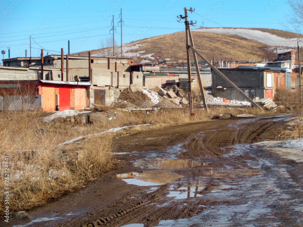 Buildings on the outskirts of the city. Ust-Kamenogorsk (Kazakhstan). Dirt road. Spring landscape