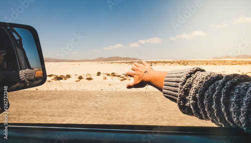 Girl close up hand playing with the wind like a wing outside the car traveling for alterntive vacation with desert and mountains outdoors view - holiday summer car travel tourism concept