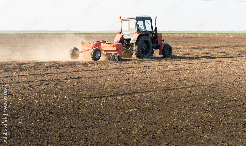 Obraz premium Farmer with tractor seeding sowing crops at agricultural field