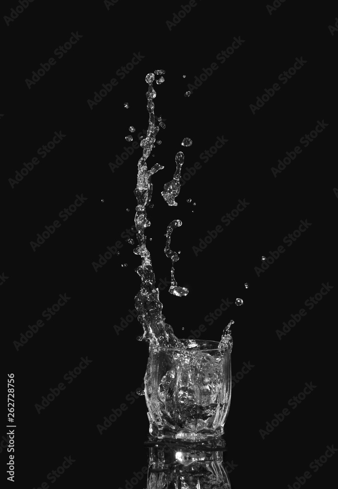 Glass of drinking water. From a glass of water splashes with reflection on a dark background.