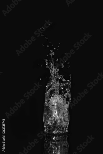 Glass of drinking water. From a glass of water splashes with reflection on a dark background.