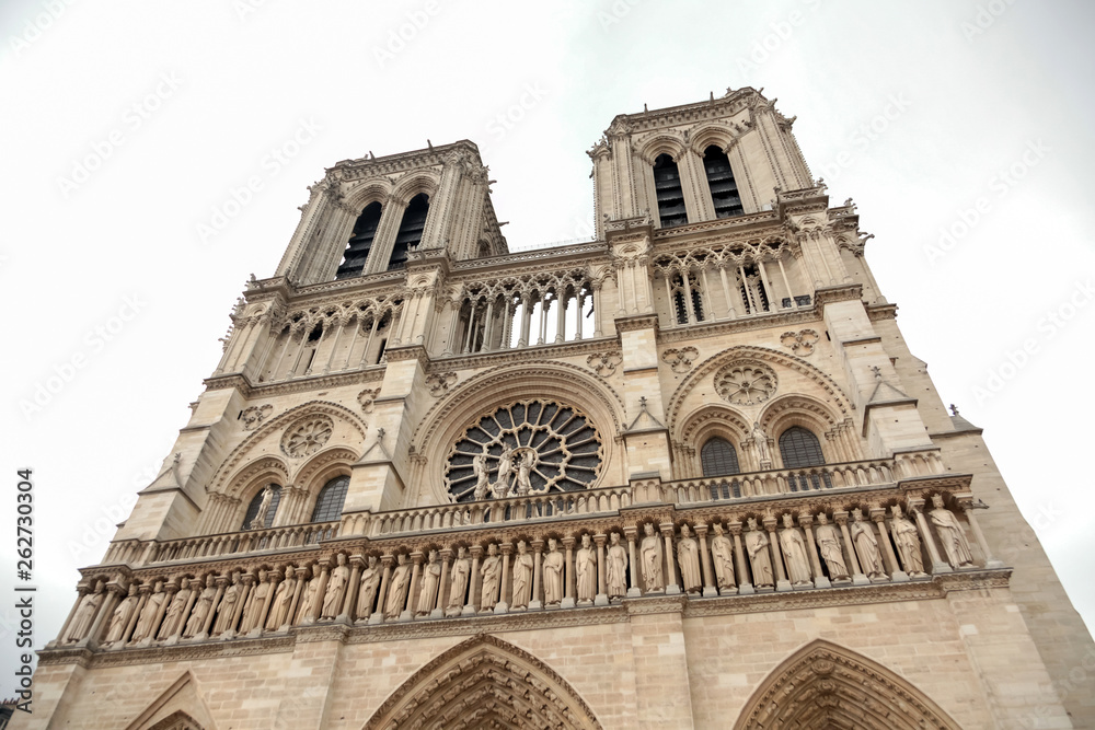 Notre Dame de Paris Cathedral. Fragment of western facade with two towers and statues. Located in Paris, France