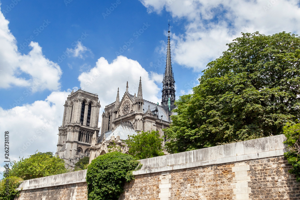 Notre Dame de Paris Cathedral before the fire. Southern facade with rose window and a spire on a roof. Sunny summer day