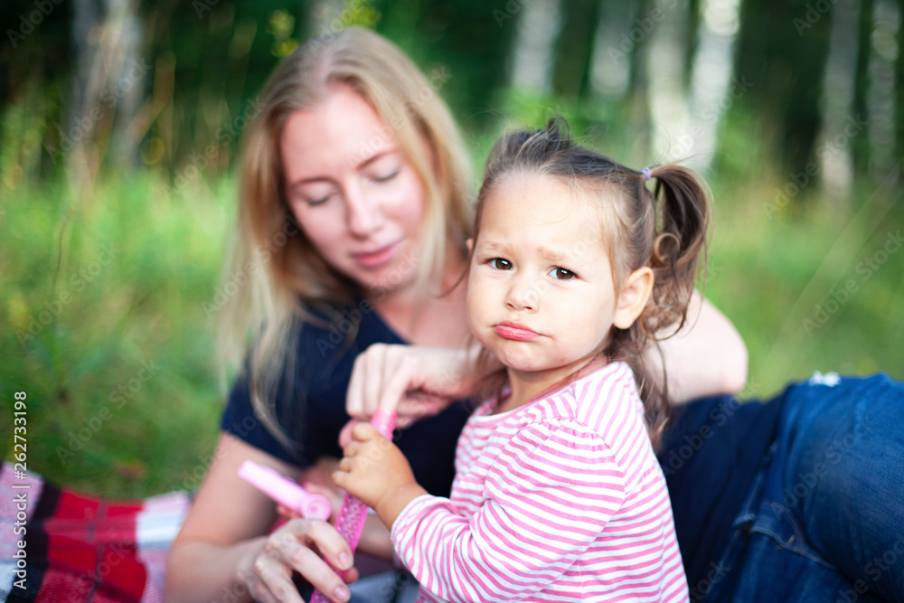 Mother and little daughter blowing soap bubbles in park. Happy and carefree childhood. Good family relations. Mother and little daughter blowing soap bubbles in park. Happy and carefree childhood. Good family relations.