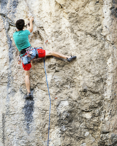 Man rock climber. Rock climber climbs on a rocky wall. Man makes hard move.