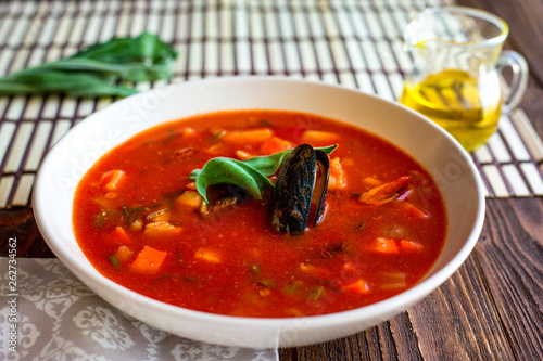 Tomato soup with mussels and seafoods. Oil. Homemade. Dinner. Basil. Traditional.