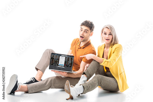 handsome excited man holding laptop with linkedin website on screen while sitting near pretty woman on white photo