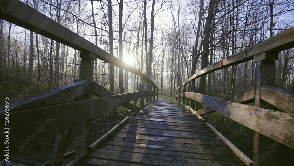 Walk over a wooden bridge at sunrise
