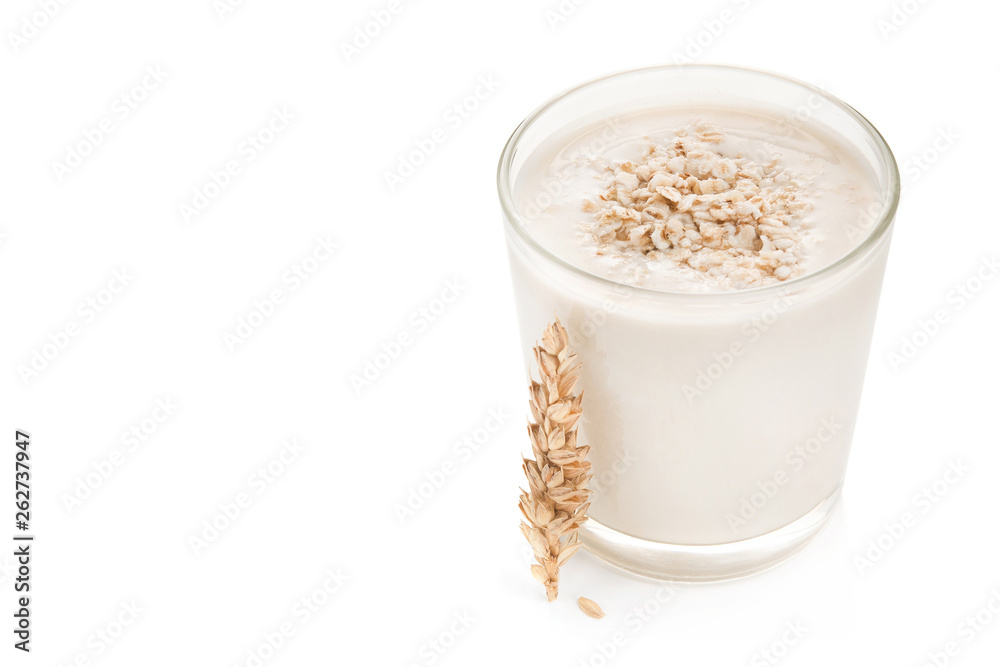 Glass of oat milk and grains on top Glass of oat milk and grains on top