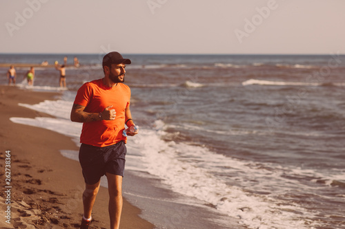 Young man jogging on the beach by the sea