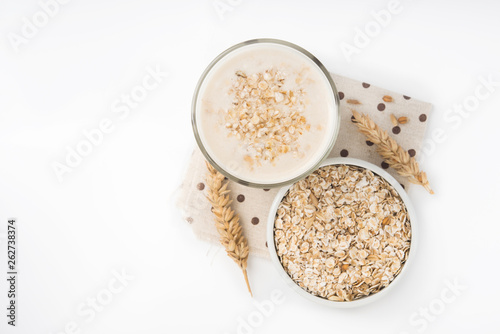 Glass of oat milk and grains in white bowl