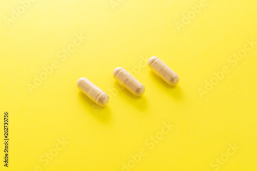Herbal medical capsule on a yellow