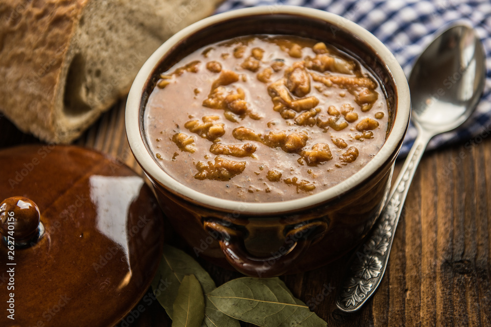 tripe stew sauce in brown ceramic pot on a wood table 