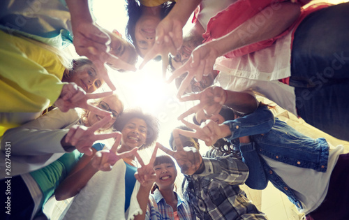 education, friendship, gesture, victory and people concept - group of happy international students or friends standing in circle and showing peace or v sign photo