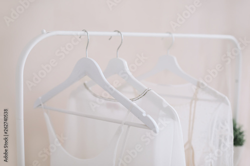 White dresses on a hanger. Minimalism concept. Set of women wedding dresses on a wooden hangers, fashion background, close up