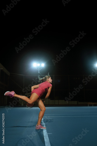 Girl at night on the court.Girl playing tennis