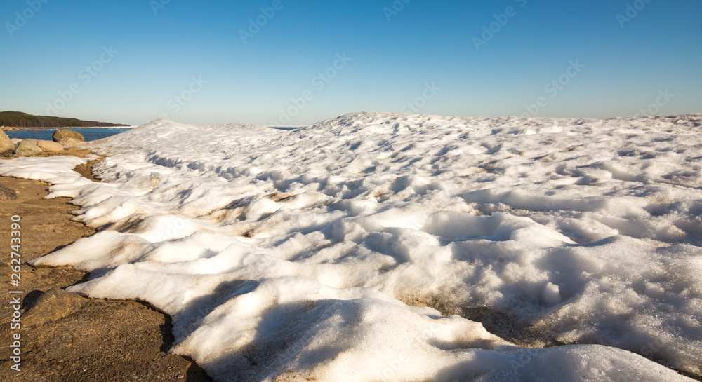 Snow pile, hill. Large snow drift isolated on a blue sky background, outdoor view of ice blocks at frozen finland lake in winter Snow pile, hill. Large snow drift isolated on a blue sky background, outdoor view of ice blocks at frozen finland lake in winter