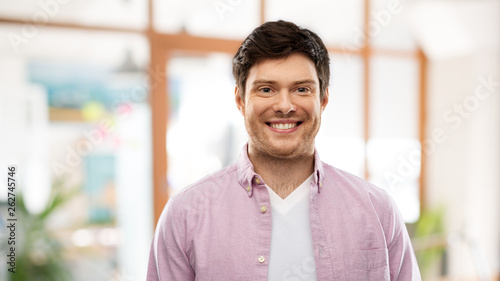 people concept - smiling young man over office room background